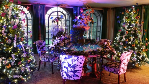 A fountain of butterflies and flowers on the dining table and colourful butterflies among garlands and Christmas trees in the Dining Room at Chartwell